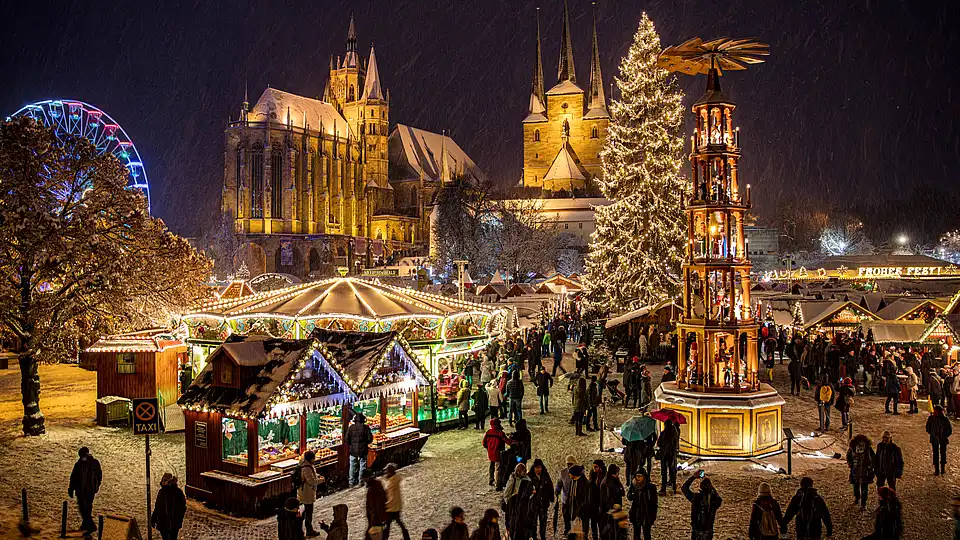 Nächtlicher Domplatz im Schnee: Karussell, leuchtende Pyramide, Christbaum und „Frohes Fest“-Schrift