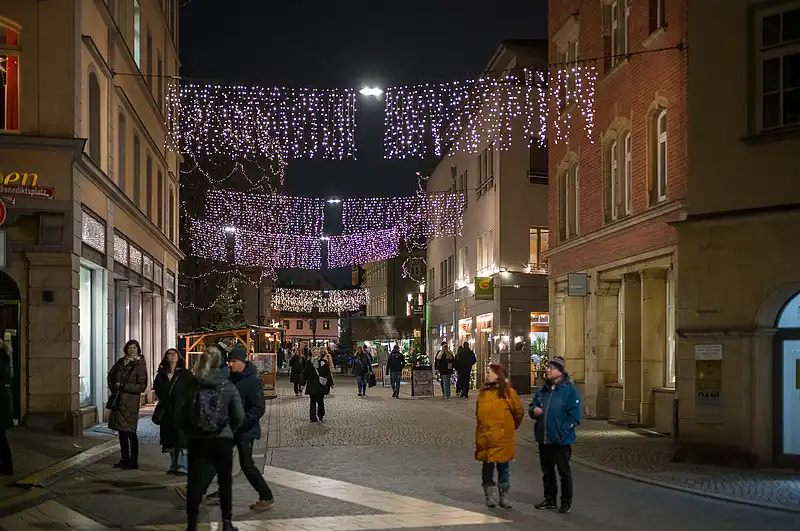 Weihnachtsmarkt bei Nacht auf der Rathausbrücke, lange Lichterketten über dem Weg, Passanten in Winterkleidung