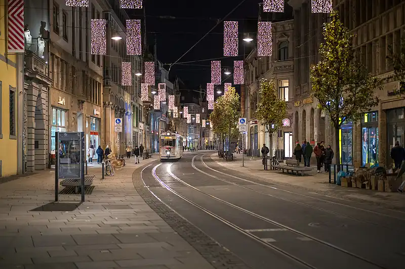 Weihnachtlicher Blick auf den Anger: geschwungene Tramschienen und hängende Lichtsäulen in der Nacht.