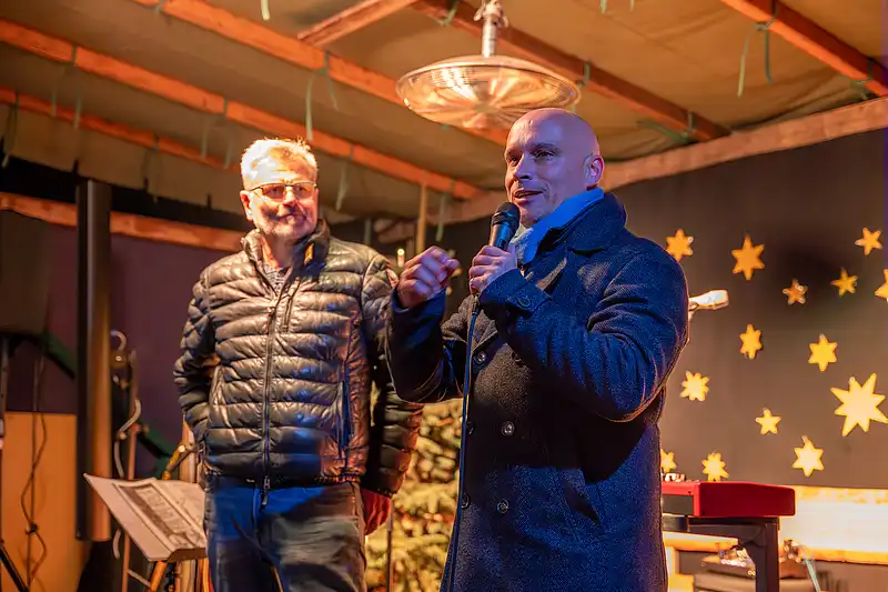 Pfarrer Christoph Knoll und Oberbürgermeister Andreas Horn vor Sternkulisse mit Scheinwerfern.